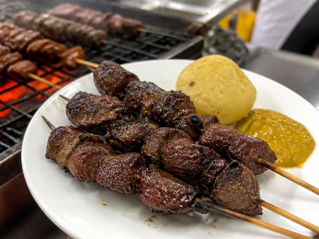 Grillattuja tummia lihavartaita lautasella keitetyn perunan ja keltaisen chilikastikkeen kanssa